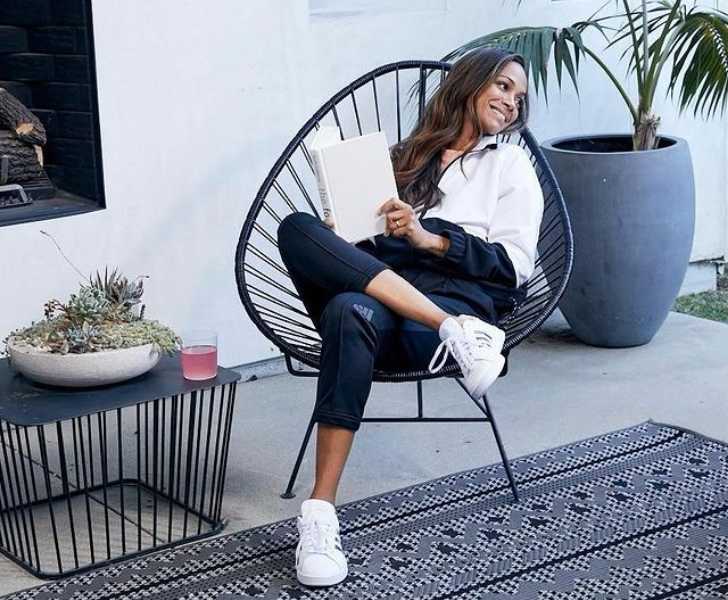 Picture of Zoe Saldana reading book sitting on chair posing for photo.